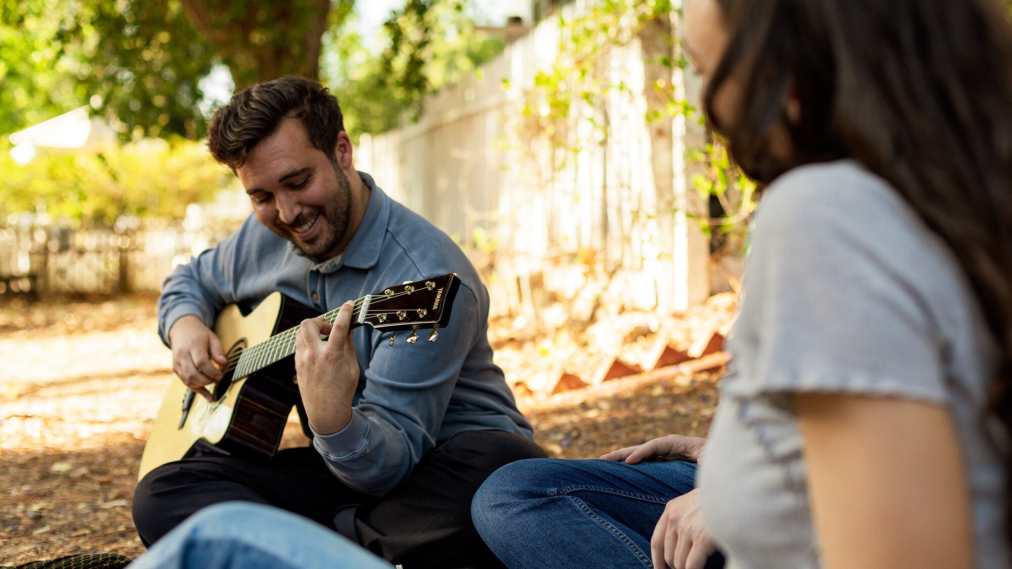 Man smiling while playing the TAS3 C acoustic guitar outdoors